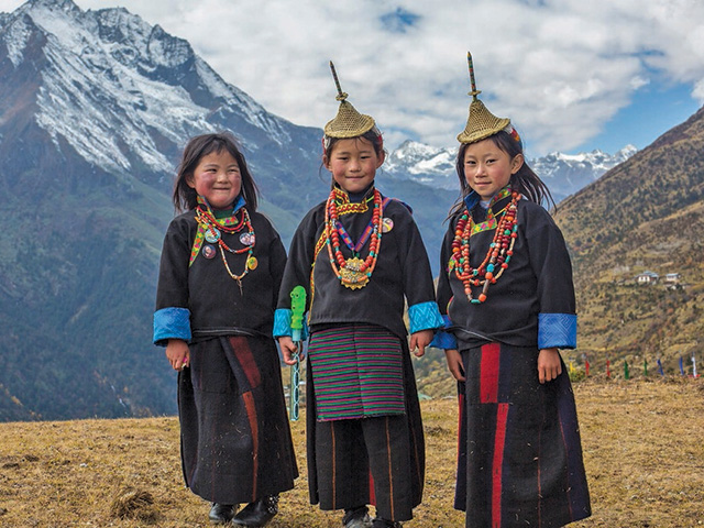 Children in traditional Bhutanese dress on a hillside near Gasa